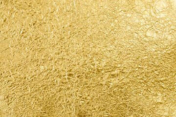 Crumpled golden tin foil surface, top view. Abstract full frame textured silvery background.
