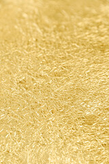 Close-up of crumpled golden tin foil surface. Focused on the front, selective focus. Abstract full frame textured background.