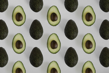 photo of whole and half avocados on a white background in a seamless diagonal pattern