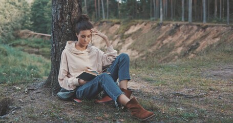 woman reading book on nature