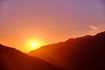 Rising sun with rays over the crests of the mountains; sunny background