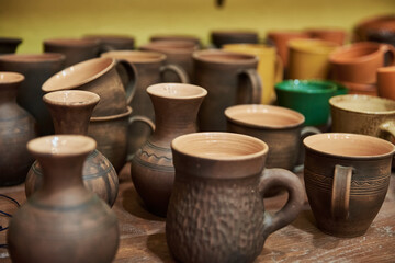 Fototapeta na wymiar Many handmade clay jugs on shelf in workshop