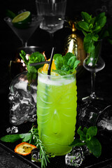 Tropical delicious green alcoholic cocktail - Jungle Juice. On a black stone background. Menu bar. Alcohol.