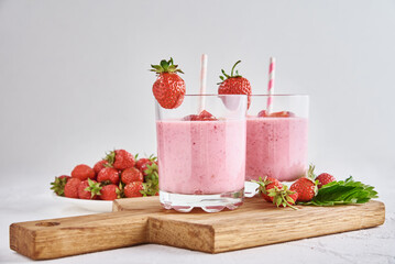 Strawberry milk shake in glass with straw and fresh berries on a white background