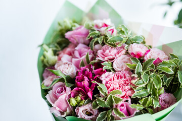 Close-up beautiful luxury bouquet of mixed flowers. the work of the florist at a flower shop. Spring bouquet. Bright bouquet including roses, lisianthus, pink carnation and green leaves