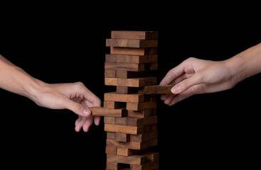 Male hand playing wooden blocks tower game on black background,Stack balancing toy