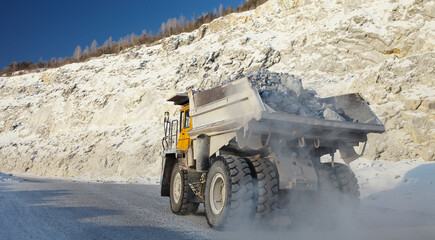 Stone ore in the back of a heavy mining dump truck during transportation to the quarry, panorama, close-up. Mining industry. © esalienko