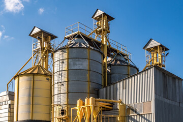 silver silos on agro-processing and manufacturing plant for processing drying cleaning and storage of agricultural products, flour, cereals and grain. Granary elevator.