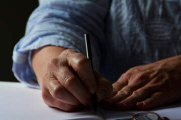 Notizen machen, Hand einer Frau schreibt in ein Heft, Nahaufnahme einer schreibenden Hand