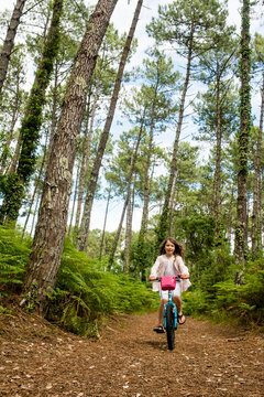 cute little girl riding a bike in a beautiful pine forest