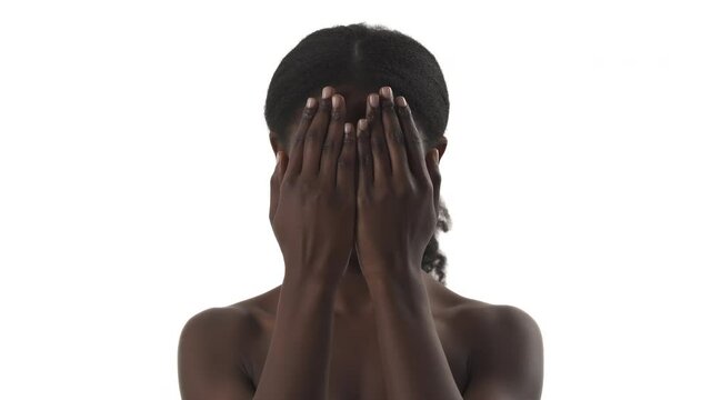 Portrait of young black woman playing in peekaboo game, hiding her face by hand and showing different emotion on white background
