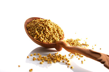 Bee pollen granules in a wooden spoon on a white background
