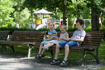 three cute siblings on a bench in park
