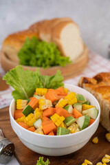 Cucumber salad, corn, carrot and lettuce in a white cup.