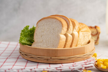 Bread in a wooden tray on a red and white cloth.