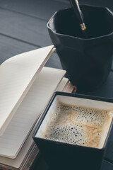 A square coffee cup with a notebook on the table. Stand for pens. - 361482868