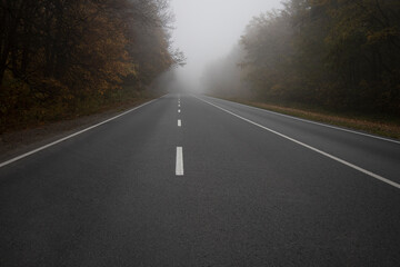 Car on the road in the fog. Autumn landscape.