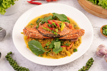 Crab stir-fried curry powder on a white plate on the cement floor.