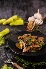 Clams fried curry powder on a black plate.
