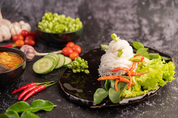 Chicken curry in a black cup with rice noodles.
