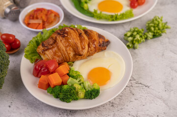 Breakfast consisting of bread, fried eggs, broccoli, carrots, tomatoes and lettuce on a white plate.