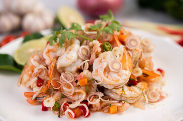 Spicy salad with shrimp on a white plate. Thai food.