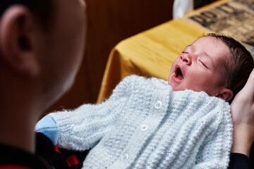 beautiful and adorable newborn baby held by his father in his hands while the baby sleeps and yawns