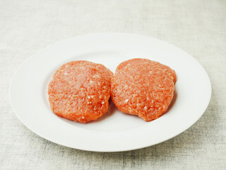 Four raw fresh turkey burgers on a white plate. Poultry product, Meat industry concept;