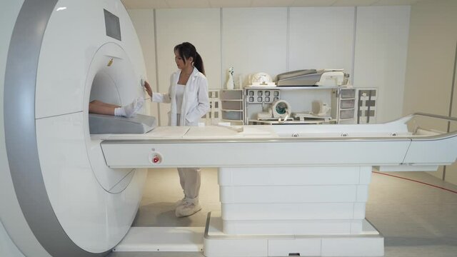 Magnetic resonance imaging, young asian woman doctor performs a magnetic tomographic examination of a boy, MRI, modern technologies in medicine, end of the procedure.