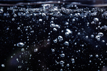Air bubbles in the water, on a black background. the water begins to boil