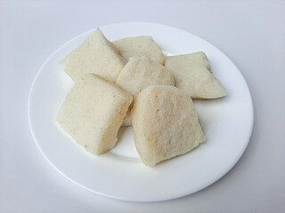 Jadah ketan, is a traditional snack from Indonesia. Made from sticky rice and grated coconut. Commonly served as tea time snack. On a white plate, isolated in white background