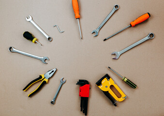 Tools top view on craft paper. Plier, open wrenches, screwdrivers and staple gun lay in circle with copy space.