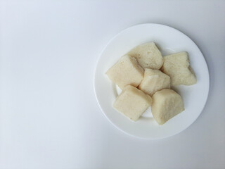 Jadah ketan, is a traditional snack from Indonesia. Made from sticky rice and grated coconut. Commonly served as tea time snack. On a white plate, isolated in white background