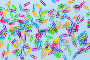 Obraz premium Notatnik spinacza kolor papieru na niebieskim tle. Leżał na płasko.