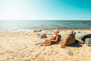 Fototapeta na wymiar Women enjoying sun on the sandy beach lying wearing a hat