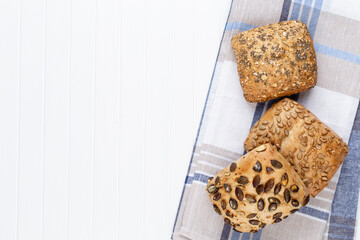 Gold rustic crusty loaves of bread and buns on wooden background. Still life captured from above top view, flat lay.