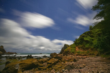 Watulumbung beach, Java Island, Indonesia with volcanic rocks and motion blur cloudy blue sky in long exposure