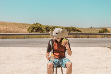 Imagen conceptual de un hombre con cabeza o mascara de elefante haciendo un descanso en el trabajo y tomando un aperitivo © minerva