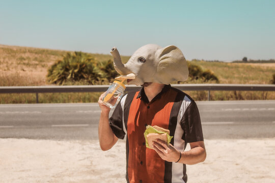 Imagen conceptual de un hombre con cabeza o mascara de elefante haciendo un descanso en el trabajo y tomando un aperitivo