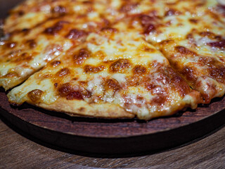 Pizza garnished with cheese on a wooden board.