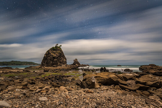 Isolated hills in Watulumbung beach, Java, Indonesia with motion blur cloudy blue sky and stars. Taken with long exposure shot