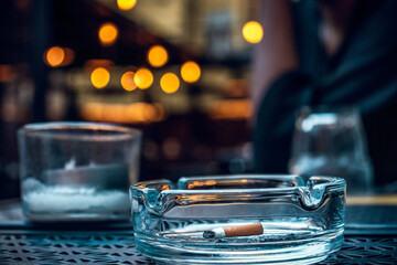 Cigarette in a glass ashtray in a bar 