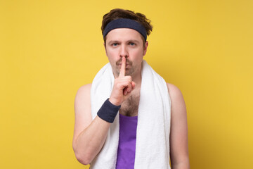 male sportsman keeps finger on lips, asks not tell secret information