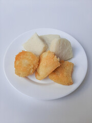 Jadah ketan, is a traditional snack from Indonesia. Made from sticky rice and grated coconut. Comparison before and after fried. On a white plate, isolated in white background