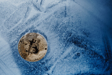 Golden symbol bitcoin frozen and covered with ice. Concept of Cryptocurrency crisis and the fall of...