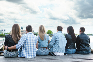 Group of people sitting on a pier beside a river