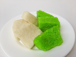 Jadah ketan (white) and wajik ketan (green), two traditional snacks from Indonesia. Made from sticky rice. On a white plate, isolated in white background