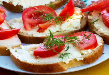 Sandwich with feta cheese, chopped garlic, sliced tomato and sprigs of dill