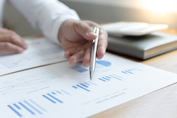 Asian business men calculate finances using graphs and calculators in the office.