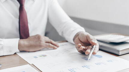 Asian business men calculate finances using graphs and calculators in the office.